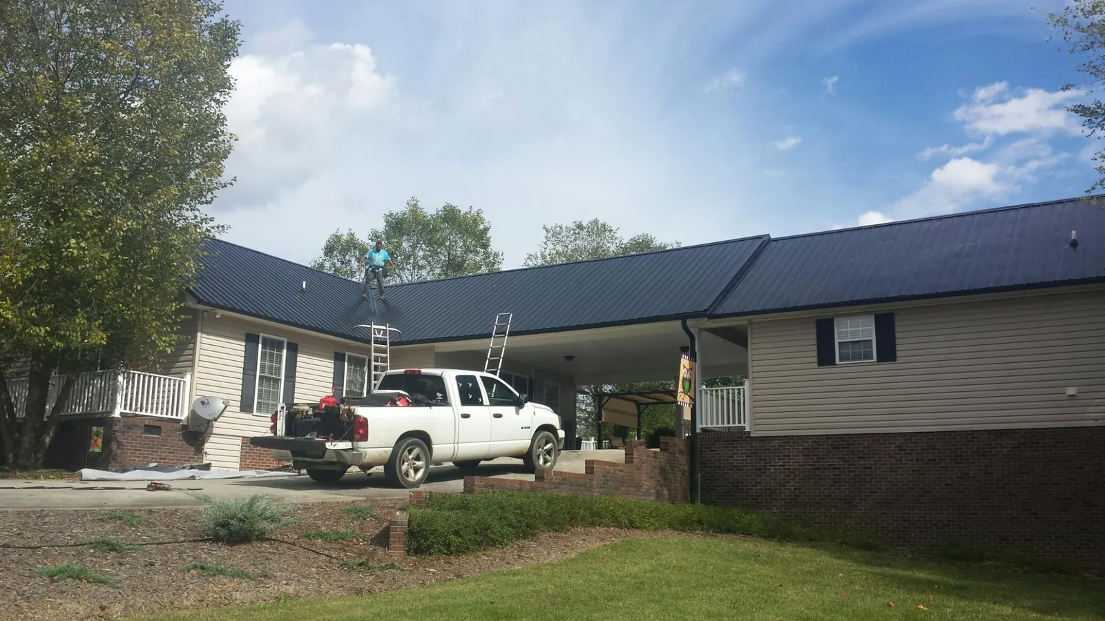 Black metal roof over a home and attached breezeway with ladders set in Elgin